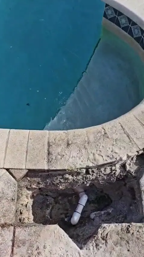 Pavers lifted and the line dug out beside the pool.